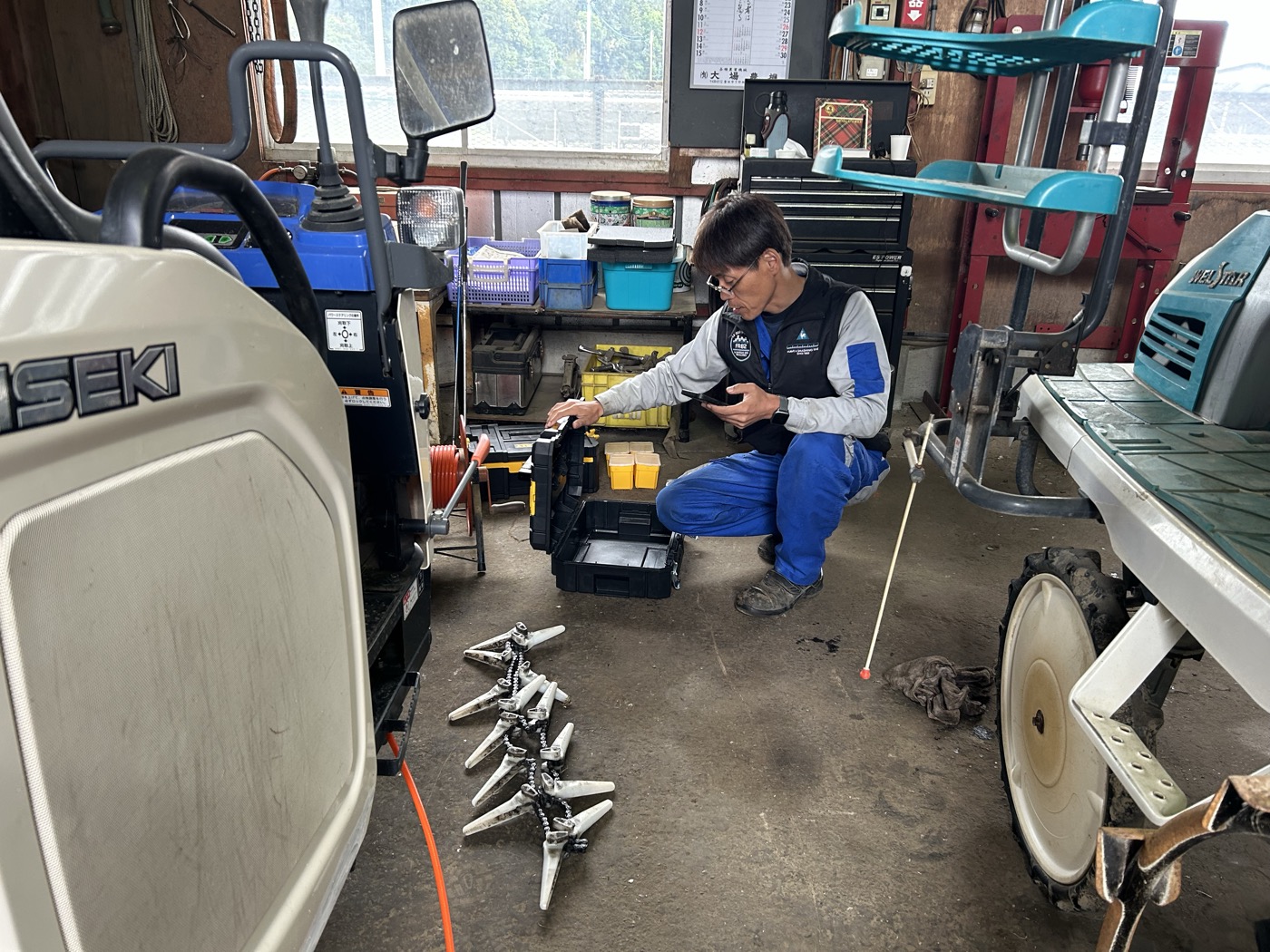 刈払機のチップソーを床に並べて確認する整備士さん