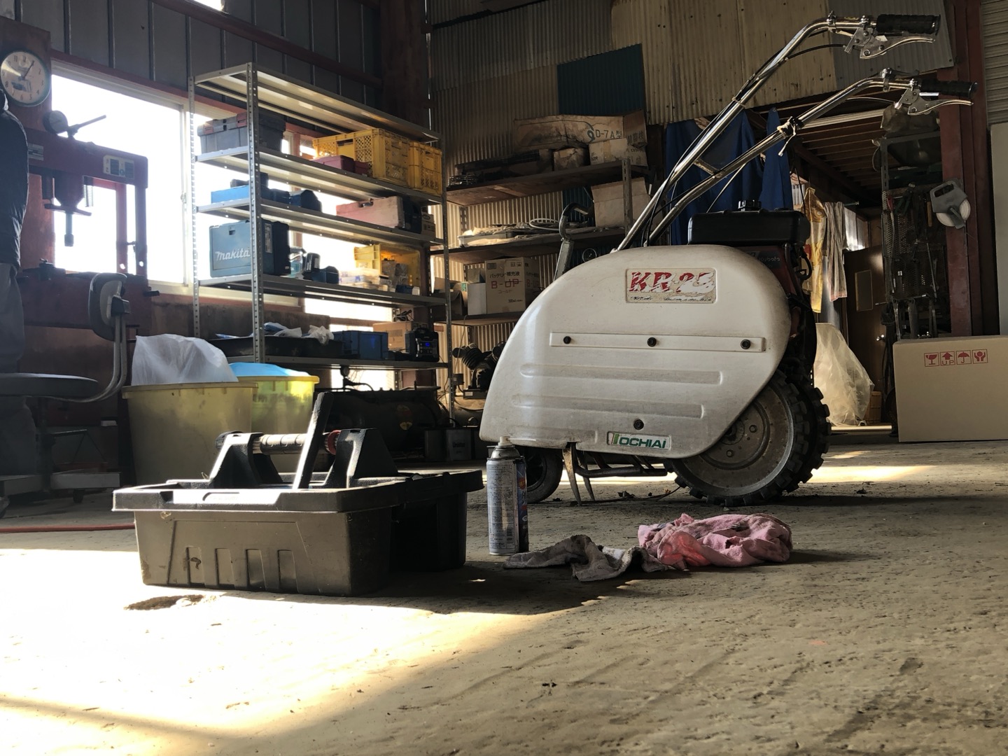整備工場の床に置かれた農機具と工具