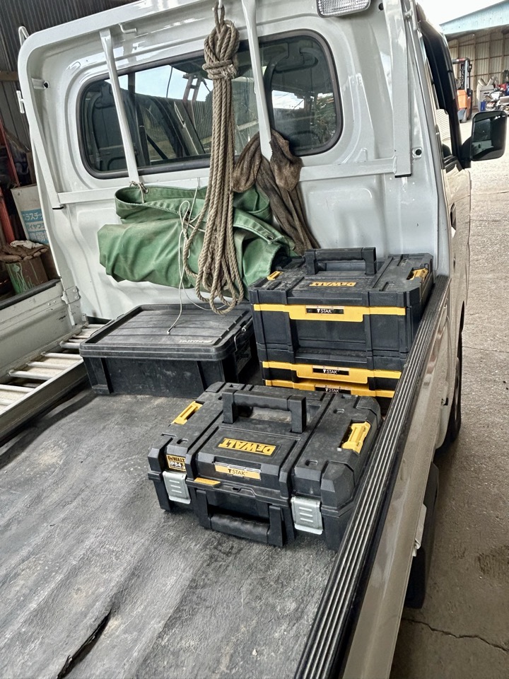 軽トラの荷台にDEWALTの工具ケースを積んで出張修理の準備をしている様子