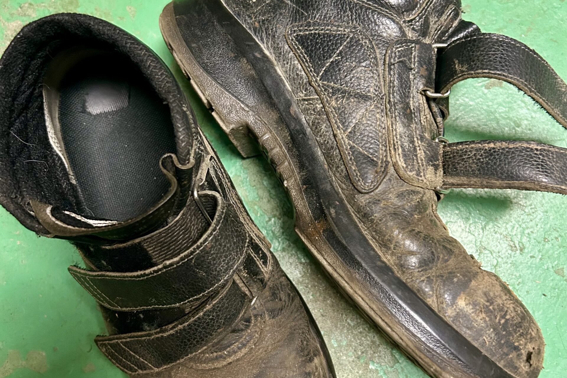 長年履き込まれ、つま先がすり減った黒いハイカット安全靴