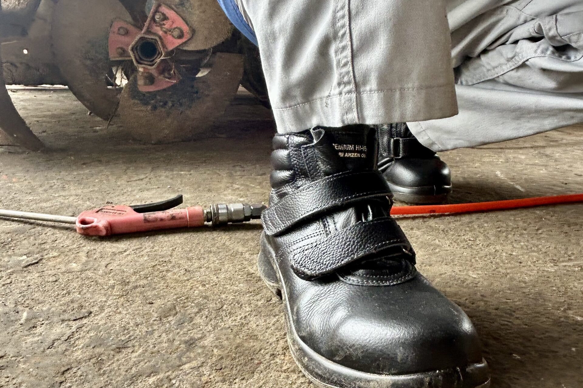 新しい安全靴を履いて農機具の整備作業をする整備士さんの足元