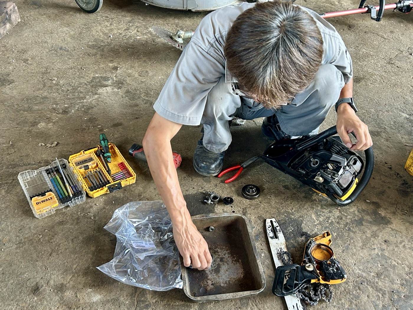 整備士さんがチェーンソーのクラッチ・スプロケット部分を分解している様子