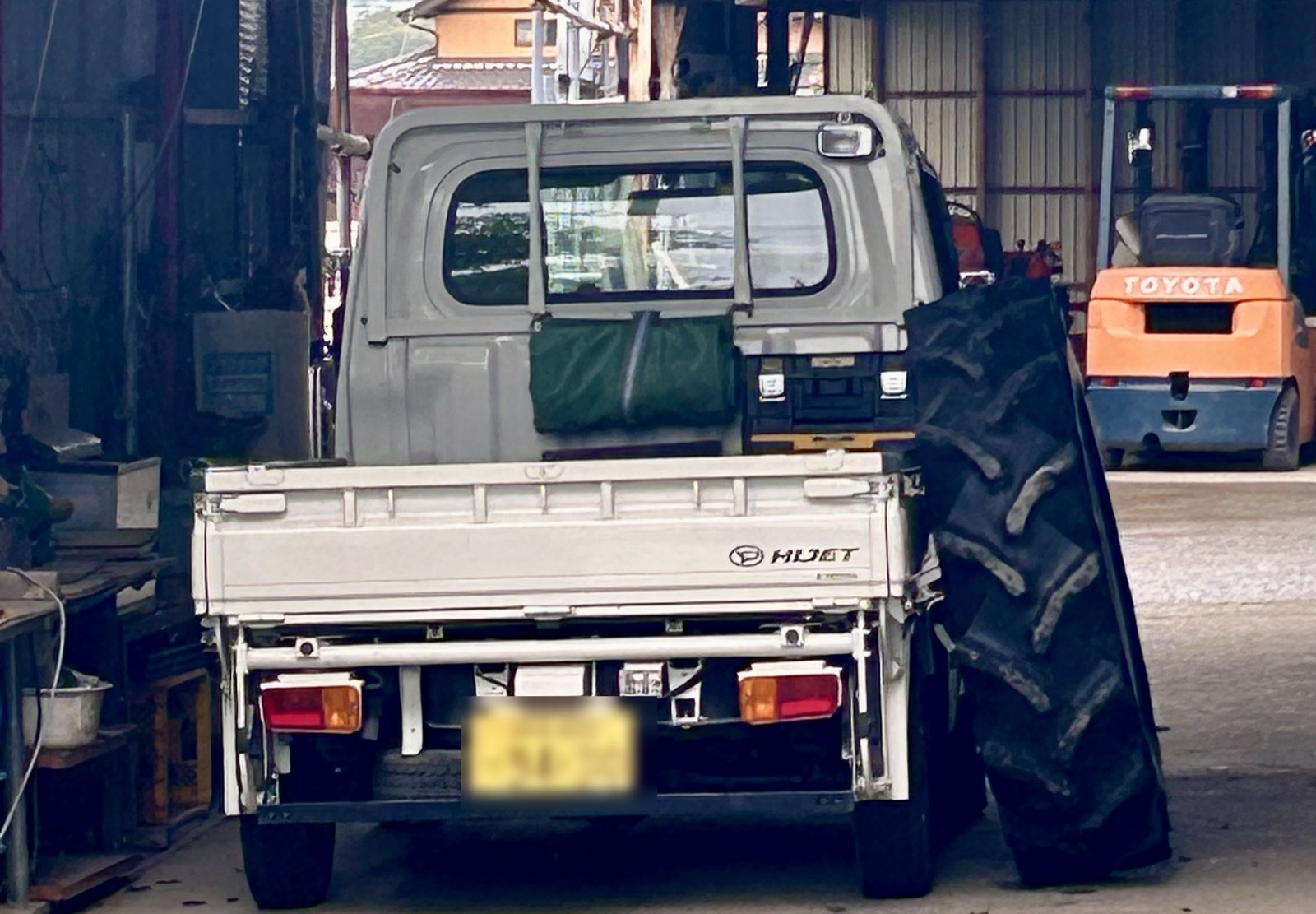 軽トラックの荷台の横に立てかけられたトラクターのタイヤ